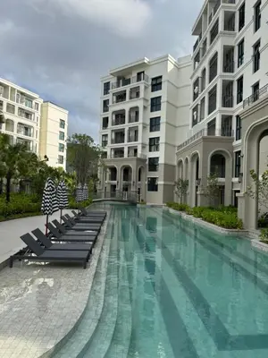a large swimming pool with chairs and buildings at Квартира в Legendary Bang Tao in Bang Tao Beach