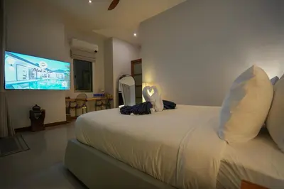a bedroom with a large bed and a flat screen tv at Villa Tropicana - Luxury 4 Bedroom Villa in Rawai Beach