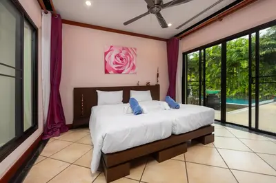 a bedroom with a bed and a large window at Baan Bua Estate Villas by TropicLook in Nai Harn Beach