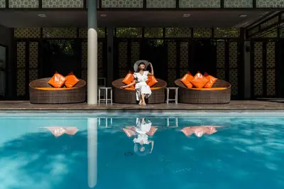 a woman sitting on a chair next to a pool at Proud Phuket, Naiyang Beach in Nai Yang Beach