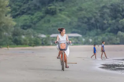 a young girl riding a bike on the beach at Proud Phuket, Naiyang Beach in Nai Yang Beach