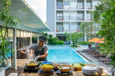 a man cooking food in front of a pool at Proud Phuket, Naiyang Beach in Nai Yang Beach