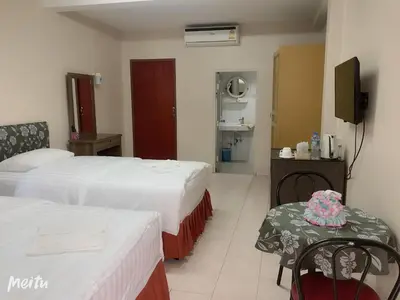 a hotel room with two beds and a table and chairs at Baan Boa Guest House in Patong Beach