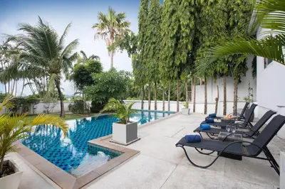 a patio with a pool and chairs and palm trees at Grand 5BR Pool Villa Sea la Vie in Rawai Beach