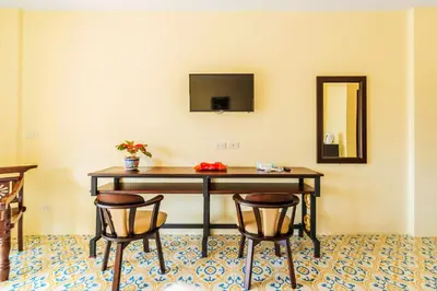 a desk with two chairs and a television on a wall at Le Hua Hotel in Phuket Town
