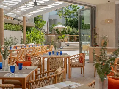 a restaurant with tables and chairs and a patio at Andaman Beach Hotel Phuket - Handwritten Collection by Accor in Patong Beach