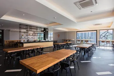 a restaurant with wooden tables and chairs and windows at Maya Phuket Airport Hotel-Naiyang Beach in Nai Yang Beach
