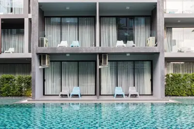 a building with chairs and a swimming pool at Maya Phuket Airport Hotel-Naiyang Beach in Nai Yang Beach