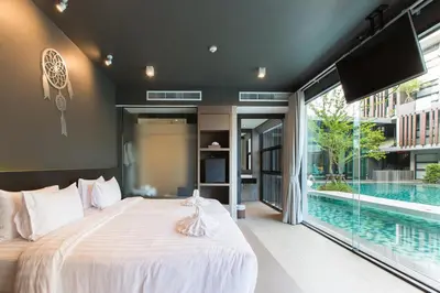 a bedroom with a large bed and a swimming pool at Maya Phuket Airport Hotel-Naiyang Beach in Nai Yang Beach