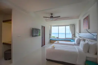 a bedroom with a bed and a view of the ocean at Norn Talay Surin Beach Phuket in Surin Beach