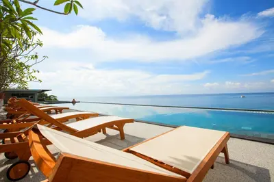 a pool with chairs and a view of the ocean at Norn Talay Surin Beach Phuket in Surin Beach