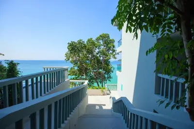 a stairway leading to a balcony with the ocean in the background at Norn Talay Surin Beach Phuket in Surin Beach