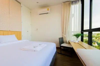 a bedroom with a bed and a desk and a window at Hill Myna Condotel Official Account in Bang Tao Beach