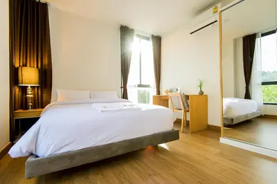 a bedroom with a large white bed and a desk at Hill Myna Condotel Official Account in Bang Tao Beach