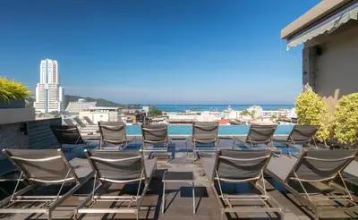 a group of chairs sitting on a balcony with the ocean at The Gig Hotel in Patong Beach
