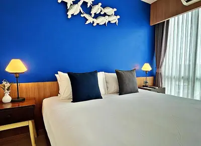 a bedroom with a blue wall and a bed at The Sixteenth Naiyang Beach Hotel- Free Schedule Airport Shuttle in Nai Yang Beach