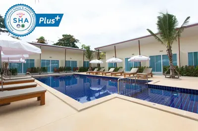 a hotel swimming pool with benches and umbrellas at Chalong Princess Pool Villa Resort SHA EXTRA PLUS in Chalong
