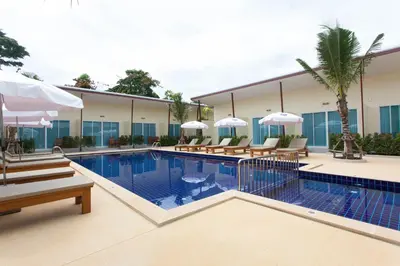 a pool in a hotel with chairs and umbrellas at Chalong Princess Pool Villa Resort SHA EXTRA PLUS in Chalong