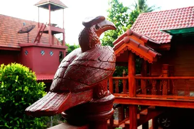a wooden statue of a chicken sitting on a fence at Ruen Tai Boutique in Nai Yang Beach