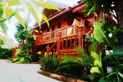 a wooden house with a porch in a garden at Ruen Tai Boutique in Nai Yang Beach