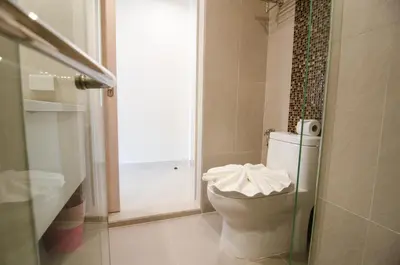 a bathroom with a toilet and a shower with a window at Centro One Bangla in Patong Beach