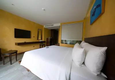 a bedroom with a white bed and a flat screen tv at Coriacea Beachfront Boutique Phuket Resort in Mai Khao Beach