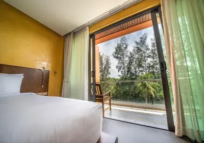 a bedroom with a bed and a large window at Coriacea Beachfront Boutique Phuket Resort in Mai Khao Beach