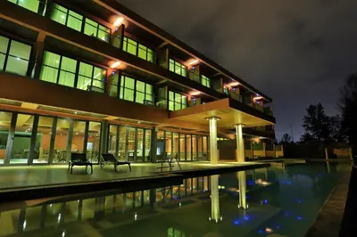 a building with a pool in front of it at night at Coriacea Beachfront Boutique Phuket Resort in Mai Khao Beach