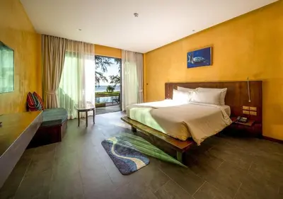 a bedroom with a large bed and a large window at Coriacea Beachfront Boutique Phuket Resort in Mai Khao Beach
