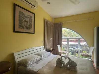 a bedroom with a bed and a large window at Phuket Paradiso in Chalong