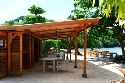a wooden pavilion with a table and tables and chairs at The Cove in Panwa Beach