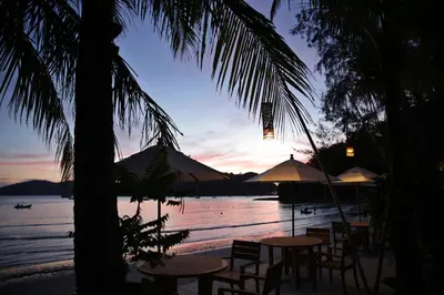 a group of tables and chairs on the beach at sunset at The Cove in Panwa Beach