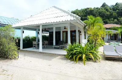 a house on the beach with chairs and palm trees at The Cove in Panwa Beach