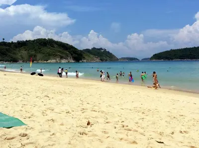 a group of people walking on a beach at Apartments in The Title Beach Rawai in Rawai Beach