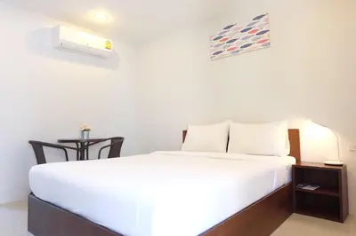 a bedroom with a white bed and a table at 3B Apartment-SHA Extra Plus in Kamala Beach