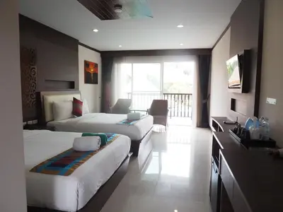a hotel room with two beds and a television at Chivatara Resort Bang Tao Beach Phuket - SHA in Bang Tao Beach