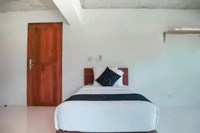 a bedroom with a white bed with a wooden door at Wabi Sabi Boutique Hotel - SHA Extra Plus in Kamala Beach