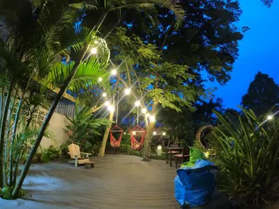 a patio at night with lights and palm trees at Cozy Garden Resort in Ao Nang Beach