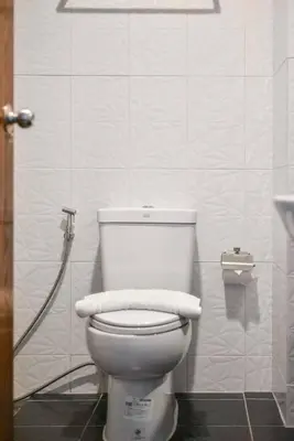a bathroom with a toilet with two towels on it at Phuket Airport Place in Nai Yang Beach