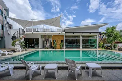 a swimming pool with chairs and a house at Phuket Airport Place in Nai Yang Beach