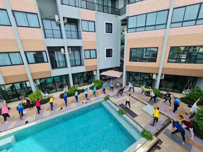 a group of people walking around a pool in front of a building at Phuket Airport Place in Nai Yang Beach