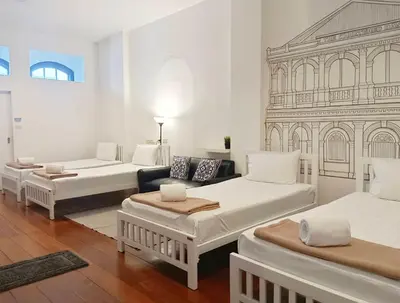 a white room with three beds and a couch at Chino Town at Yaowarat Phuket - SHA Plus in Phuket Town