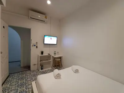 a bedroom with two beds and a tv on the wall at Chino Town at Yaowarat Phuket - SHA Plus in Phuket Town