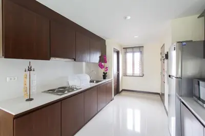 a kitchen with wooden cabinets and a stainless steel refrigerator at The Lai Thai Luxury Condominiums in Ao Nang Beach