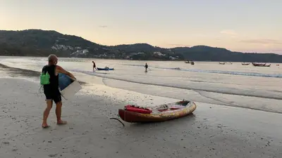a woman standing next to a boat on a beach at Kata Top Villas in Kata Beach