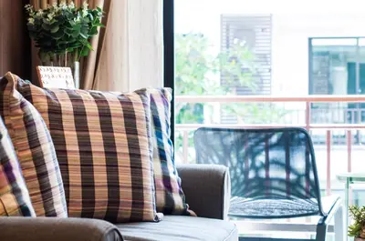 a couch with a striped pillow sitting next to a window at The Title KR Beach Condotel Rawai Beach in Rawai Beach