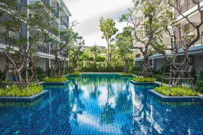 a swimming pool in the middle of a building with trees at The Title KR Beach Condotel Rawai Beach in Rawai Beach