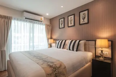 a bedroom with a large bed and a window at The Title KR Beach Condotel Rawai Beach in Rawai Beach