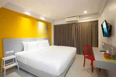 a bedroom with a large white bed and a red chair at Recenta Style Phuket Town in Phuket Town