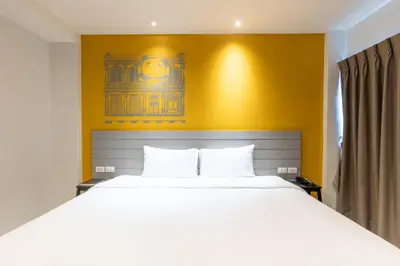 a bedroom with a white bed and a yellow wall at Recenta Style Phuket Town in Phuket Town